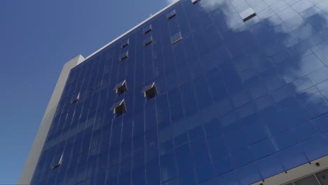 panoramic view of a mirrored building reflecting the blue sky with clouds