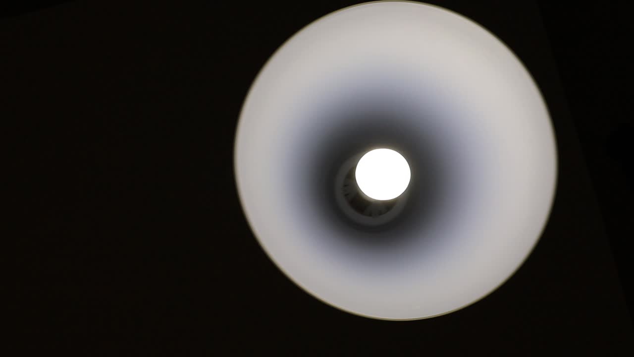 어두운 방에 매달린 흔들리는 전구