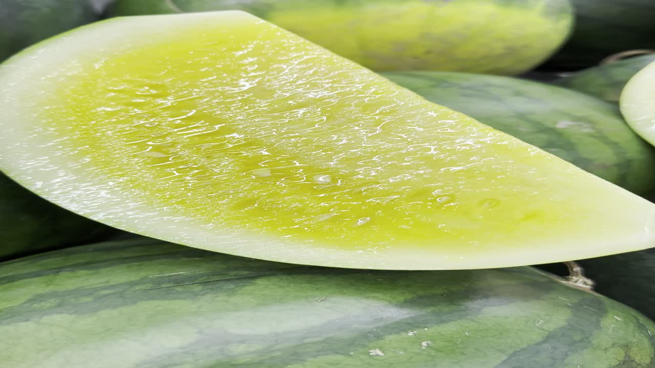 Fetta di anguria gialla fresca appoggiata su angurie intere