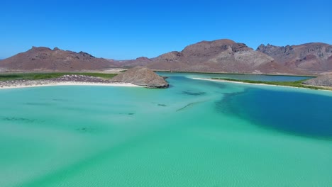 slow moving pan of white sand beaches, blue shades of water, green mangroves and mountain background