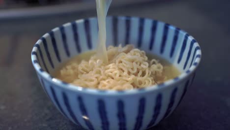 Close-up-pouring-hot-soup-over-Japanese-instant-Tonkotsu-ramen