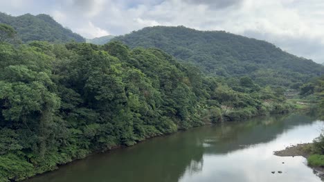 Toma-Panorámica-De-La-Pintoresca-Y-Serena-Vista-Del-Paisaje-Del-Intrigante-Río-Cerca-De-La-Cascada-Shifen-En-El-Distrito-De-Pingxi,-Nueva-Ciudad-De-Taipei,-Taiwán