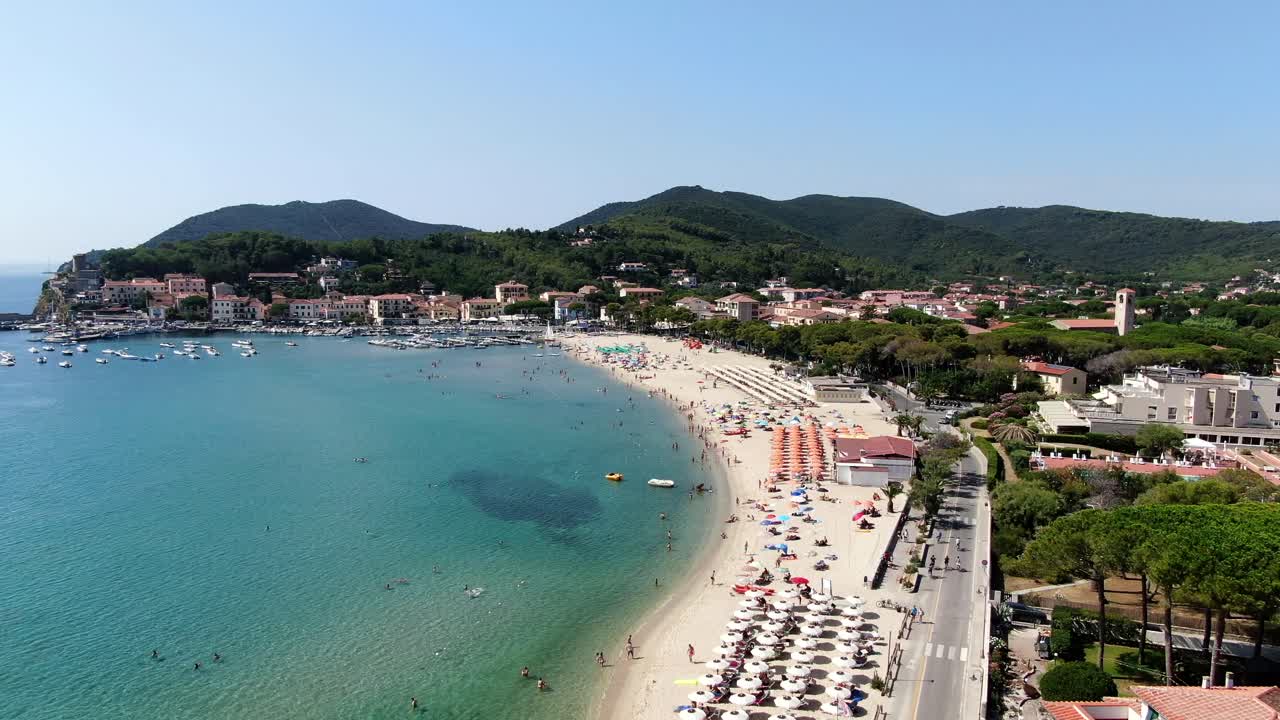 Boats, swimmers, and sunbathers fill the vibrant beach along Elba’s Mediterranean coast