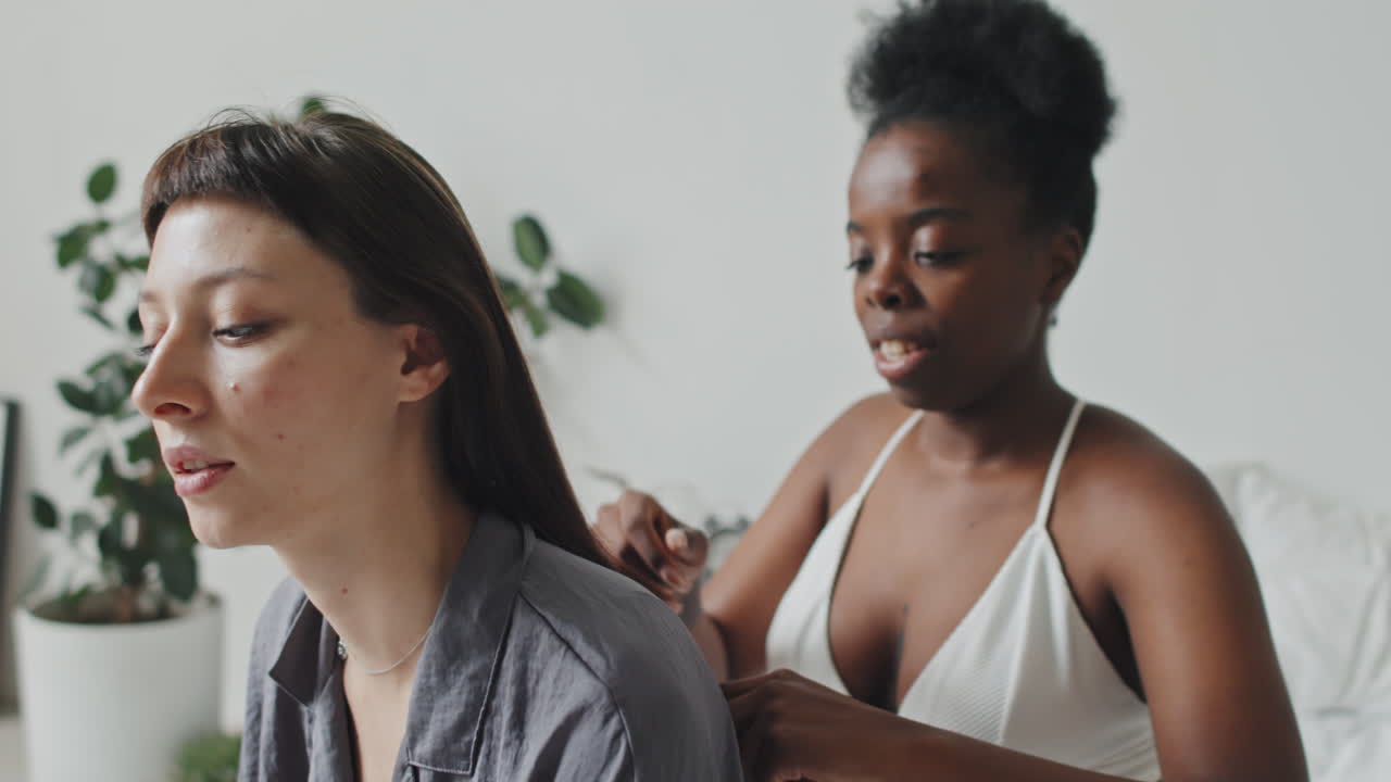 Smiling African-American Woman Brushing Girlfriends Hair