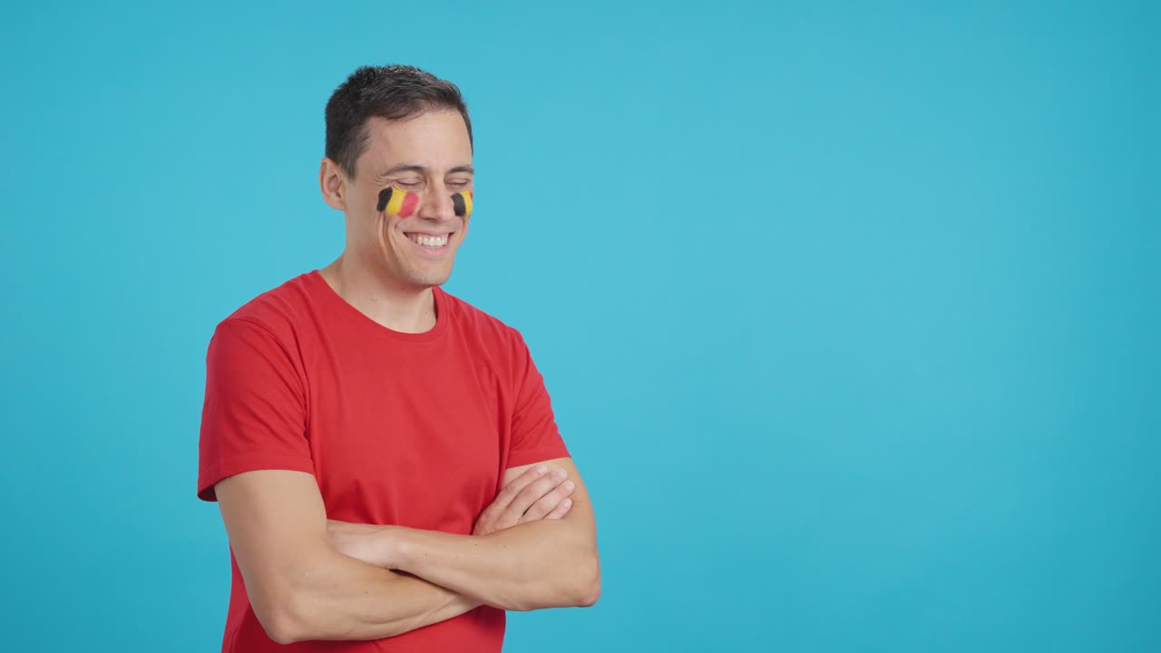 Homem feliz com a bandeira belga pintada no rosto olhando para o lado