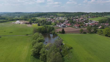 Fliegen-über-Einem-Tschechischen-Dorf-Nechánice-Mit-Einem-Teich,-Umgeben-Von-Bäumen