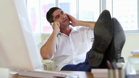 Businessman-talking-on-the-phone-with-feet-up-on-desk