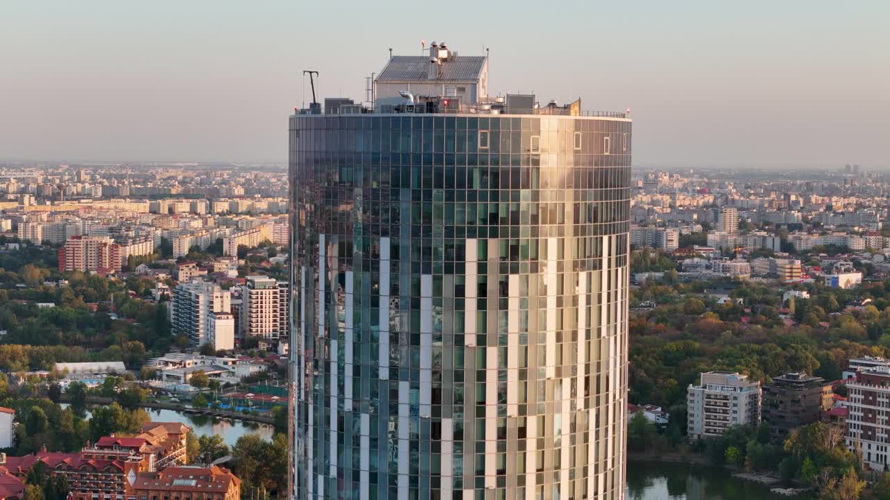vista aérea giratoria de un alto edificio de oficinas con una puesta de sol en el fondo, bucarest, rumania