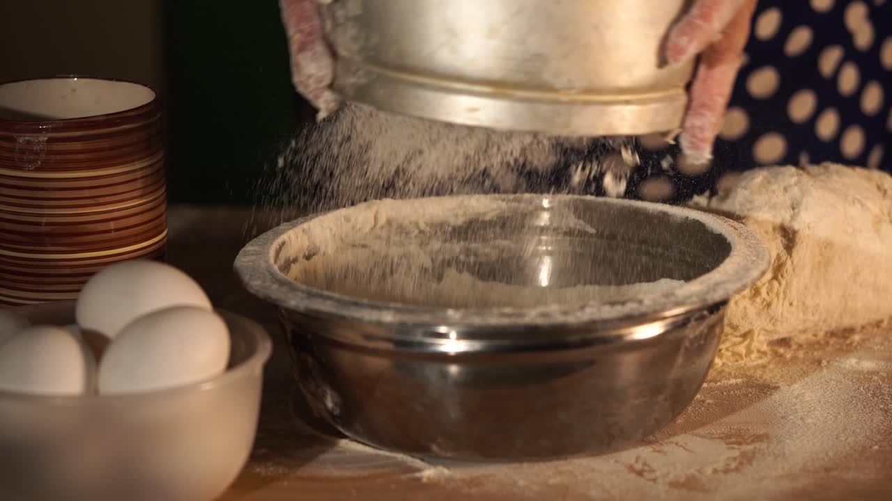 Woman sifting flour into a mixing bowl for baking