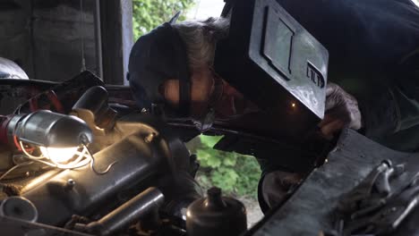 locked off view of car mechanic welding on front of car