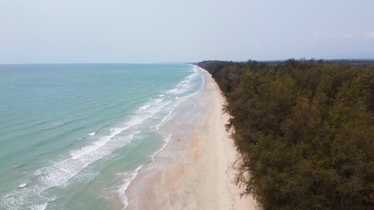 Aerial time lapse side view of Long Ocean waves reach the shore in Southern Thailand