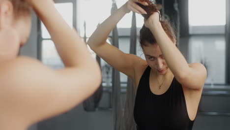 woman styling hair in front of mirror in gym