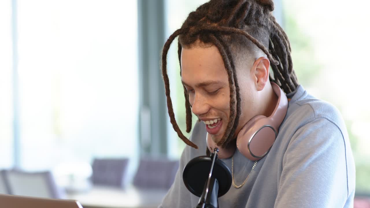 African American man adjusting microphone arm connecting cable and preparing podcast at workspace