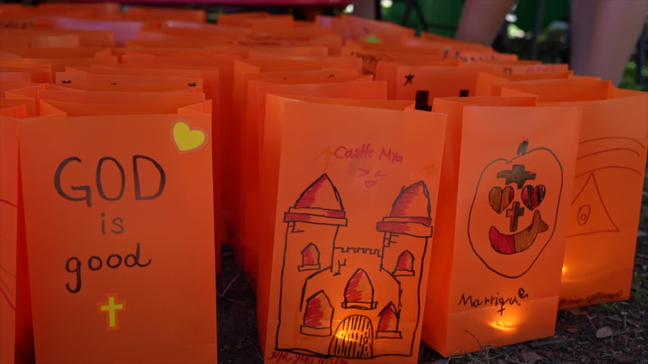 Vibrant orange lanterns with Halloween-themed artwork glow in the evening light. The scene captures creativity and festive spirit, illuminated warmly against a dark background