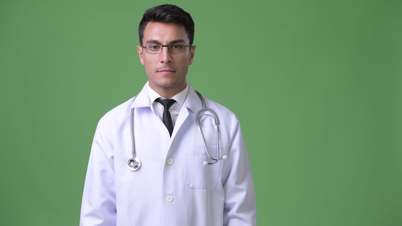 초록색 배경에 젊은 잘생긴 히스패닉 남자 의사