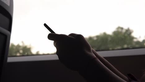 footage of girl's hands scrolling the screen on mobile phone. the girl is sitting in the train. motion. close up