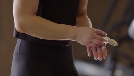 female swedish gym rat chalks up hands before weightlifting workout session