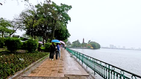 people walking with umbrellas by the river