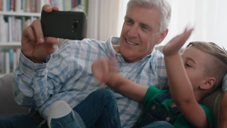 Abuelo-Y-Niño-Teniendo-Video-Chat-Usando-Teléfono-Inteligente-Niño-Pequeño-Compartiendo-Fin-De-Semana-De-Vacaciones-Con-Familia-Abuelo-Disfrutando-Charlando-Sobre-Tecnología-Móvil-En-Casa-Con-Nieto