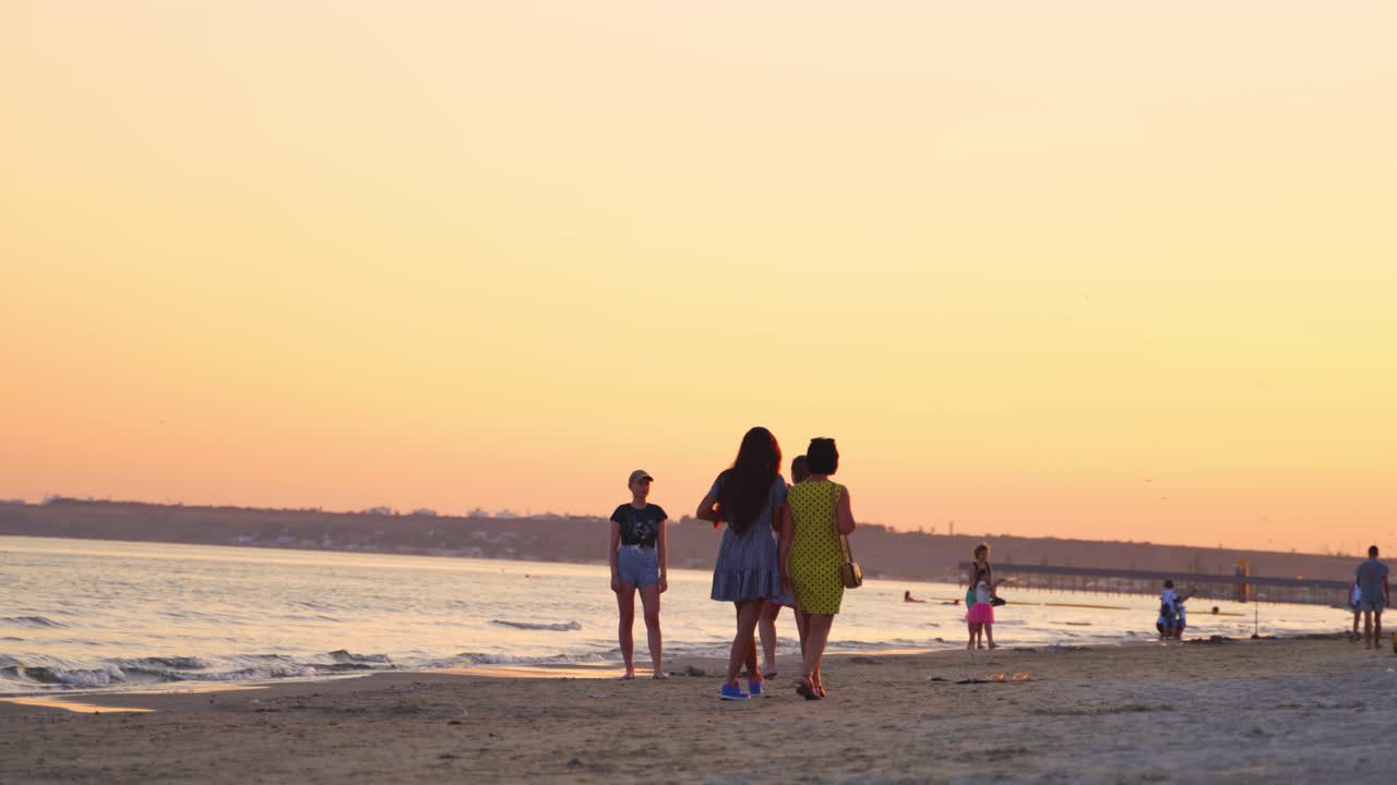 Public beach view. People having chill out on the public beach against sunset