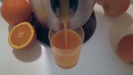 orange juice pouring in glass on white table