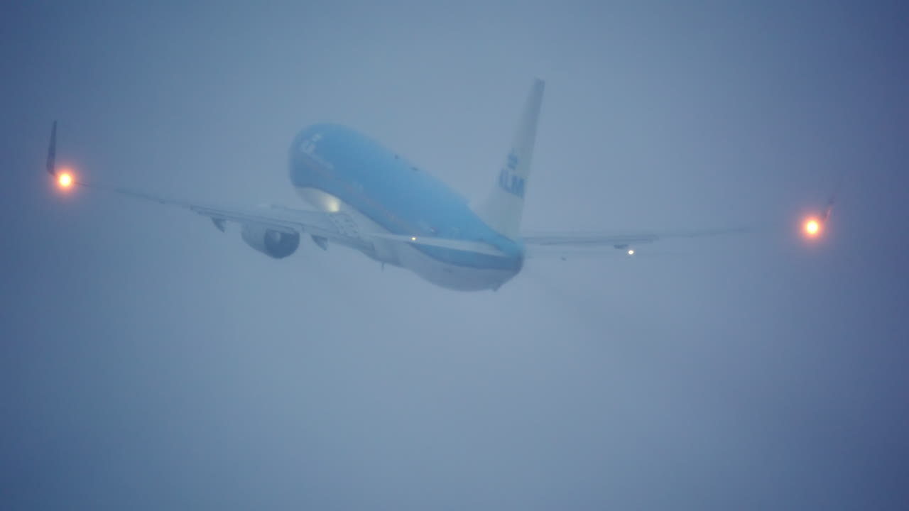 Aereo blu in ascesa nella fitta nebbia con luci di navigazione