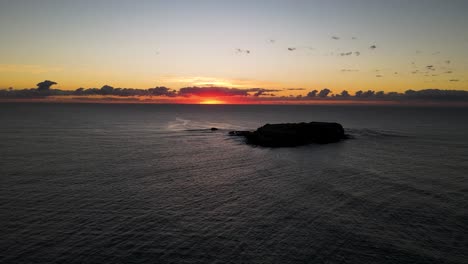 colorful morning sunrise over a calm winter ocean framed behind a silhouette of a marine park island