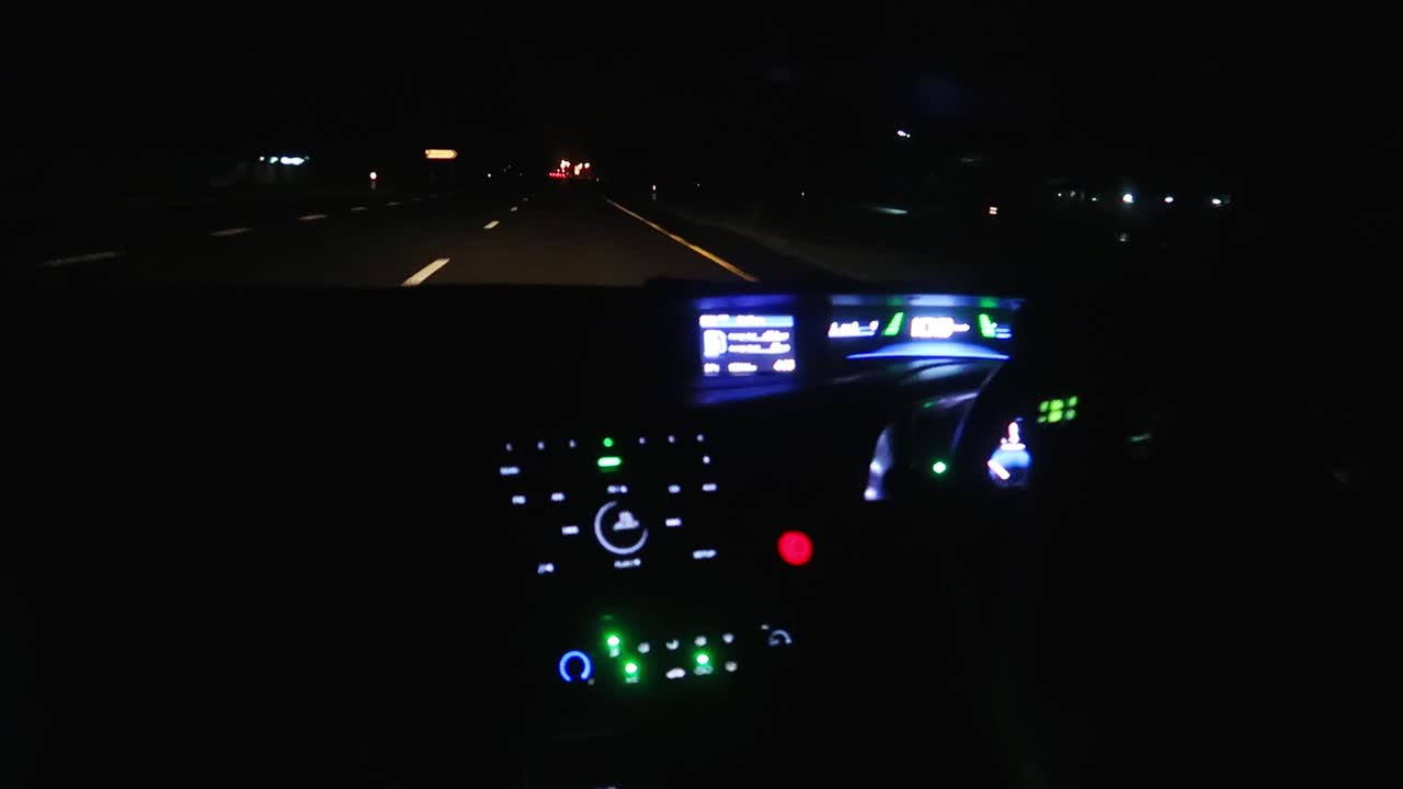 Wide shot of the Dashboard of a vehicle driving at night on the highway in Thailand.