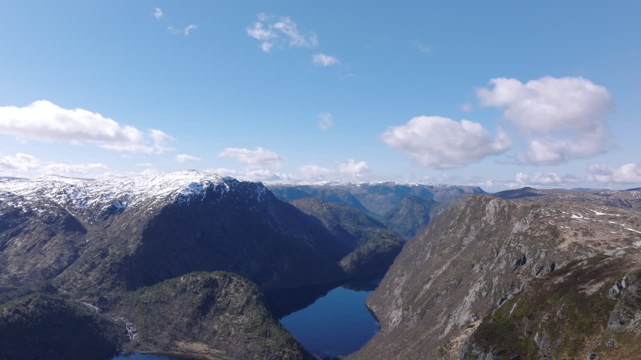 Cinematic aerial footage gliding over Matrefjellene mountains, capturing rugged peaks, snow, and springtime alpine beauty