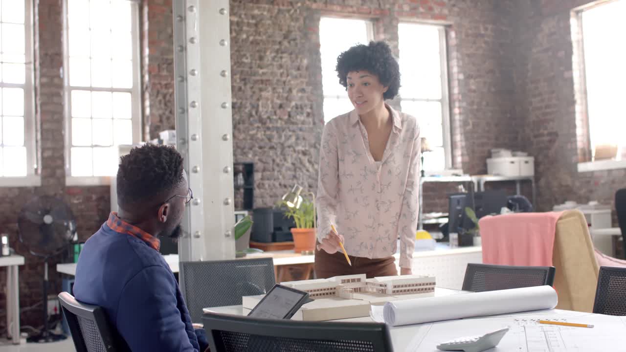 diversos colegas arquitectos enfocados discutiendo el trabajo con el modelo de construcción en la oficina en cámara lenta