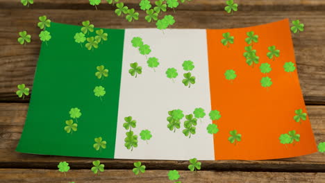 animation of green clovers floating with irish flag in background for st. patricks day