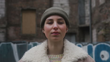 close up view of a young girl looking at camera wearing a beanie and jacket in the street