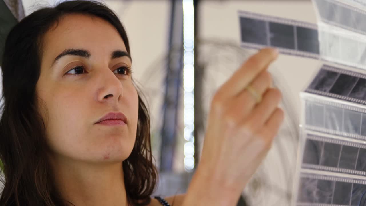 fotógrafa chequeando tiras de película en el estudio fotográfico 4k