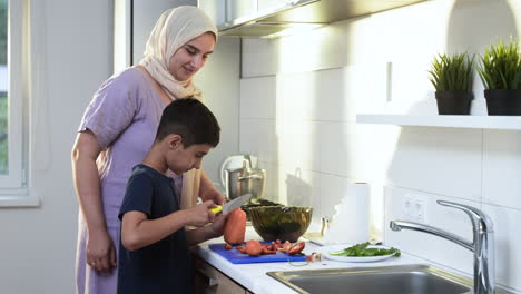 side view of mother with hiyab and her son in the kitchen.