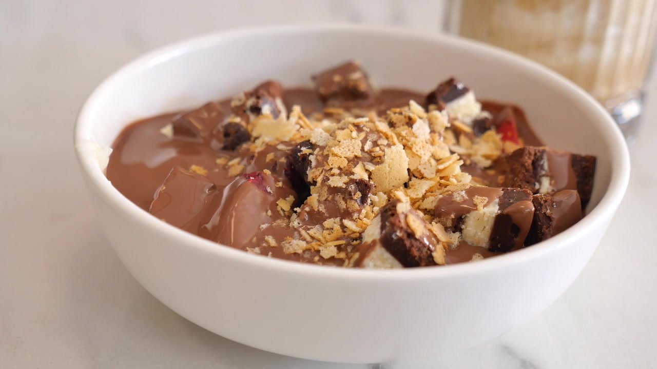 Ciotola di budino al cioccolato guarnita con pezzetti di brownie e cereali
