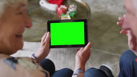 pareja caucásica mayor sonriente en sombreros de santa tablet videollamada de navidad, con pantalla verde