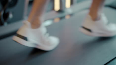 Closeup-man-feet-jogging-on-trademill-in-sport-club.-Strong-man-legs-at-gym