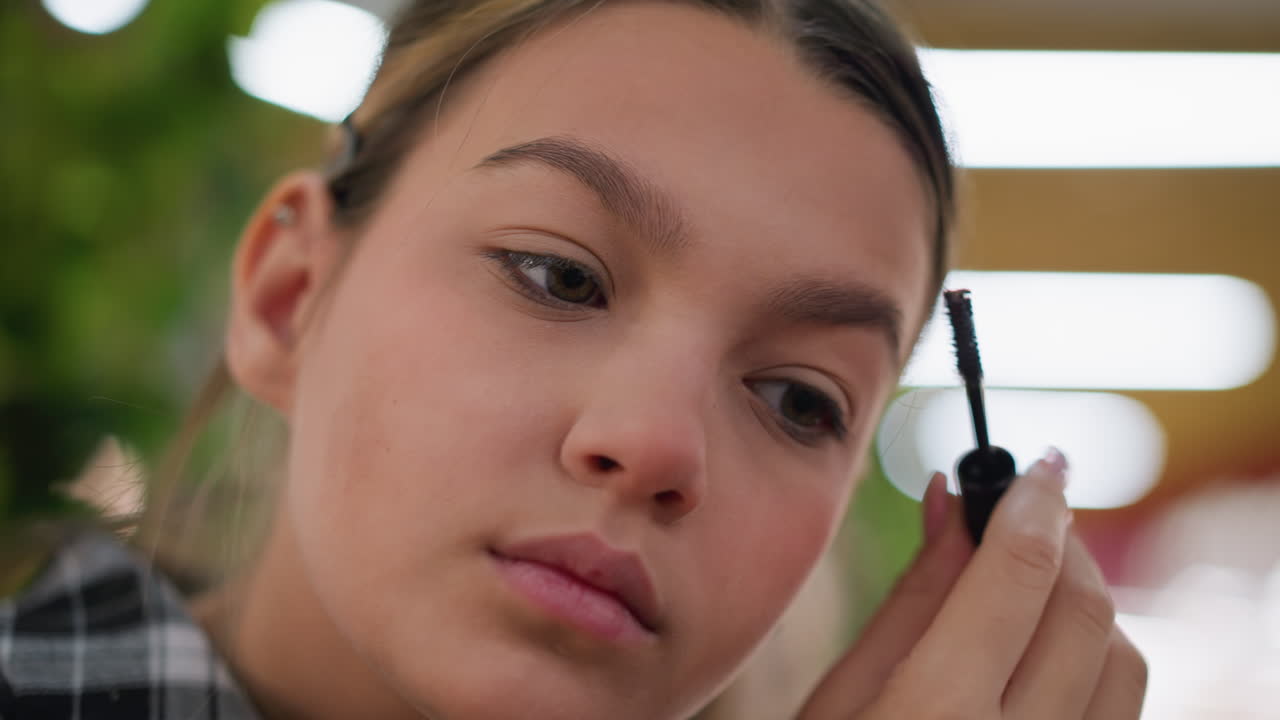 vista de primer plano de una dama cepillándose cuidadosamente las cejas con un cepillo de cejas, enfoque suave en el fondo con tonos cálidos, enfoque en el aseo de las cejas para una apariencia precisa y ordenada