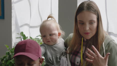 happy-business-woman-mother-holding-baby-playing-with-colleague-discussing-project-in-diverse-modern-office-workplace