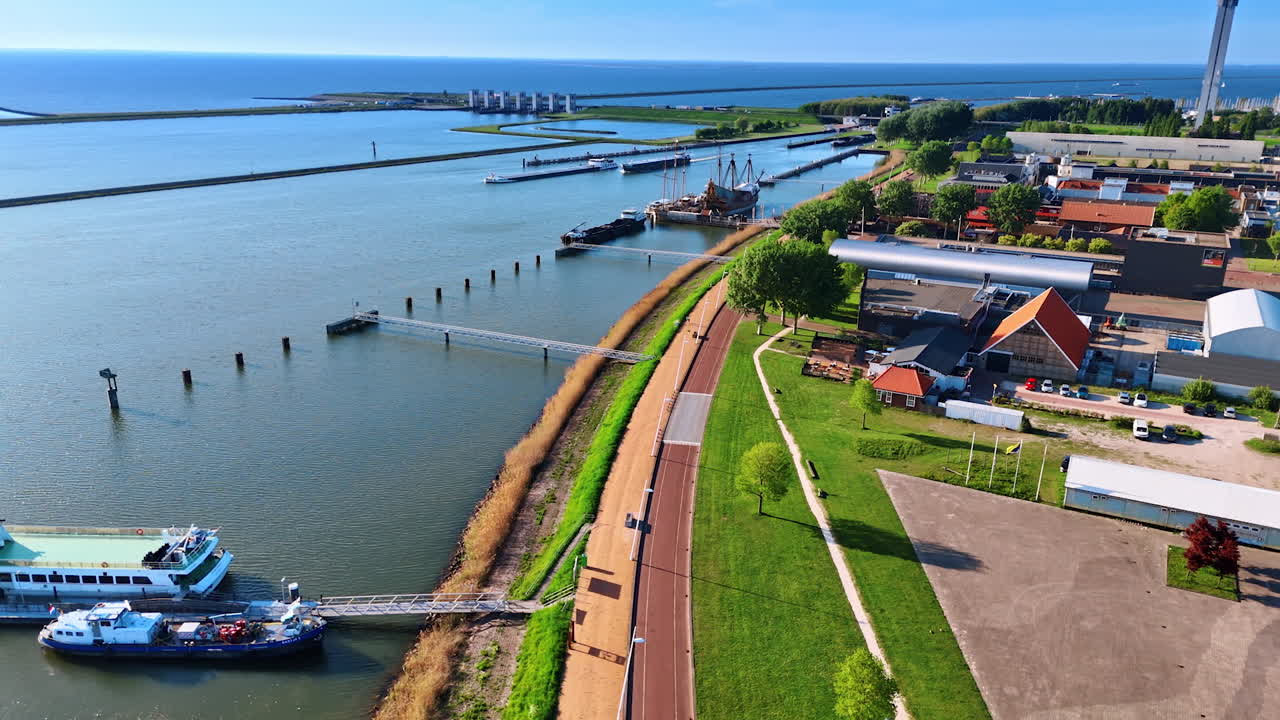 View on the lakefront of Merkemeer lake in Lelystad, the Netherlands. Approaching a historical reconstruction of a ship Batavia standing at the berth.