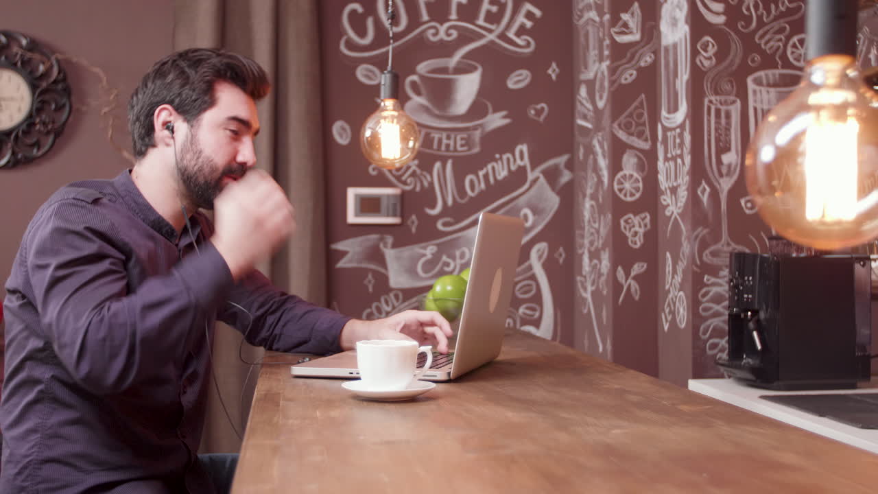 un hombre trabajando en una computadora portátil en un café