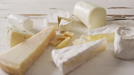 video of assorted hard and soft cheeses on rustic white wooden table top