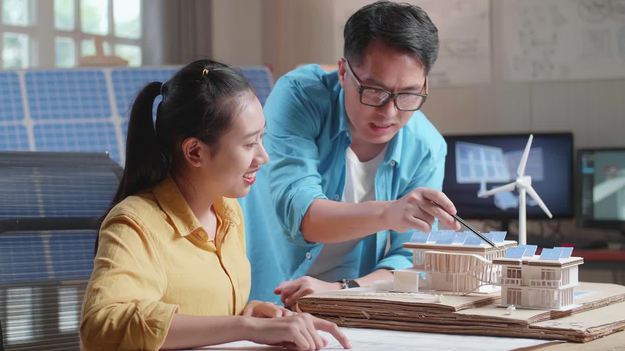 아시아인 남녀가 태양광 패널로 작은 집을 짓는 데 서로 도움을 주고 있습니다.