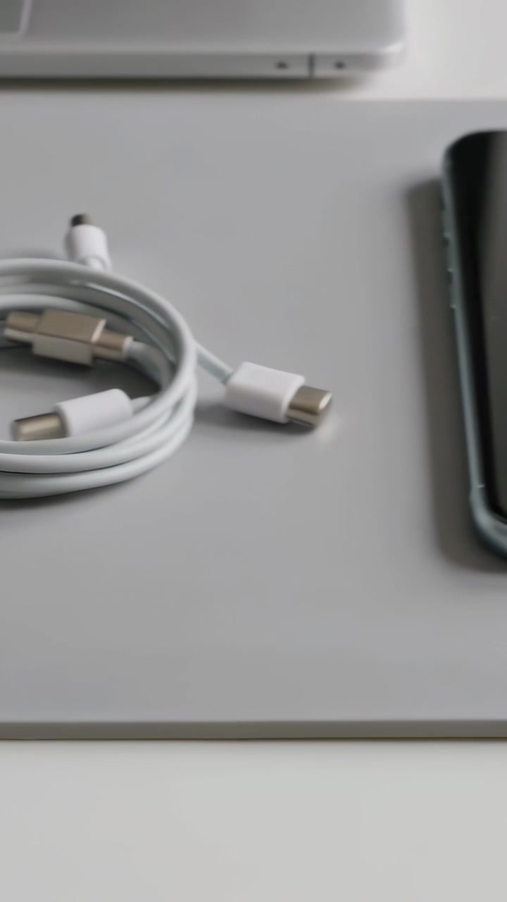 Vertical video: Camera panning showing headphones, coiled cable pointing at phone to charge on mat