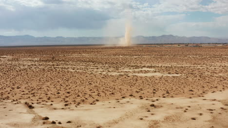 a desert sandstorm kicks up a dust devil in the mojave desert landscape - aerial view of the twister