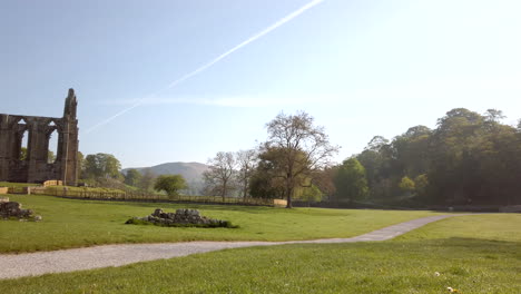 Revelación-Panorámica-De-Las-Ruinas-De-La-Abadía-De-Bolton-En-Una-Hermosa-Y-Soleada-Mañana-De-Verano-En-Yorkshire,-Inglaterra,-Con-Un-Destello-De-Lente