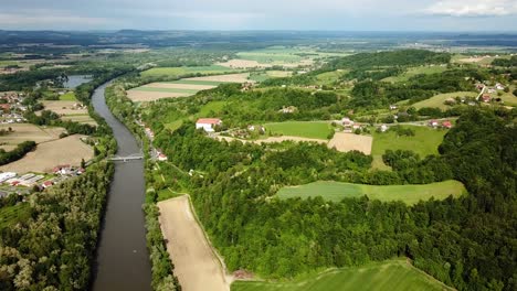 Toma-Aérea-Del-Paisaje-Del-Río-Mura-Y-El-área-Circundante-Con-Casas-Y-Agricultura-Austria-Eslovenia-Europa