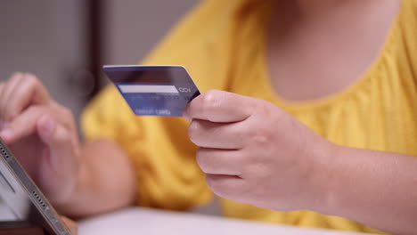 mujer codificando la información necesaria para comprar algunos artículos vendidos en línea usando un teléfono móvil y una tarjeta de crédito