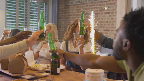 multi-cultural group of friends celebrating birthday with party and cake at home together