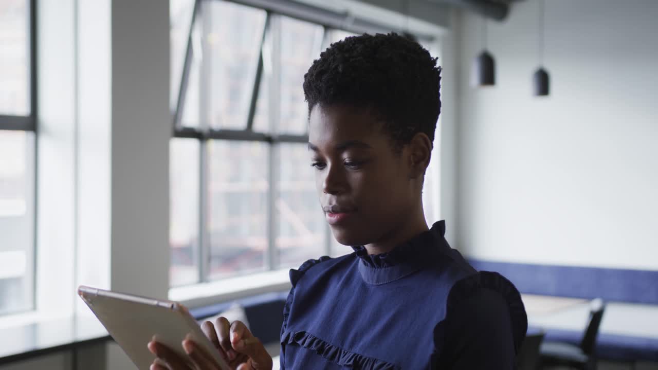 Mixed race businesswoman standing using digital tablet in office